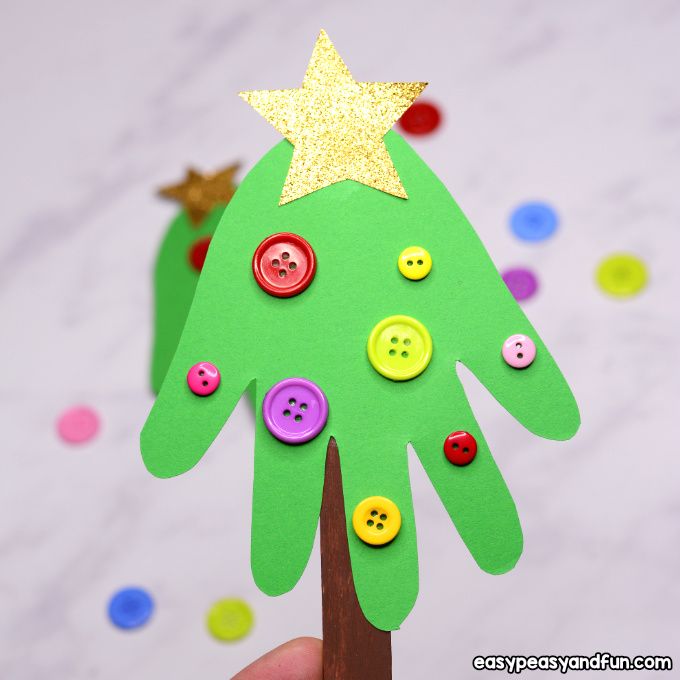 a hand holding a green paper christmas tree with buttons on it and a gold star