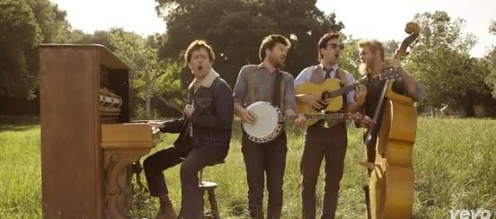 three men are standing in the grass with their instruments and one man is playing an instrument