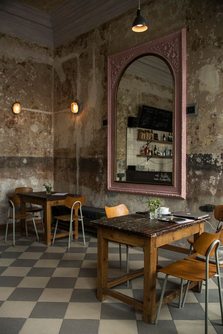 an empty restaurant with tables and chairs in front of a large mirror on the wall