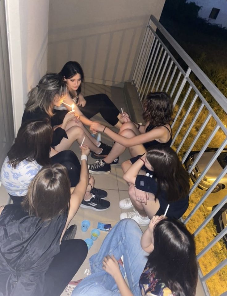 a group of young women sitting on the floor next to each other holding lit candles