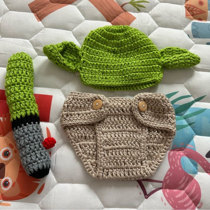 two crocheted baby items are laying on a quilt