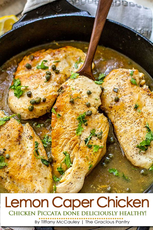 lemon caper chicken in a cast iron skillet with a wooden spoon on the side