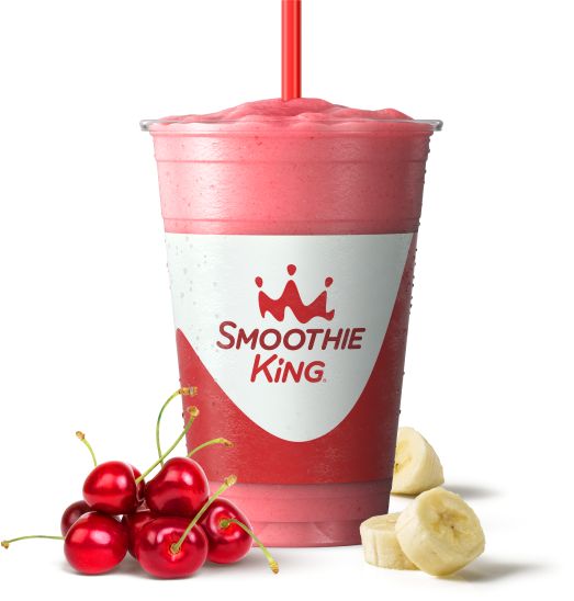 a smoothie cup next to some bananas and cherries