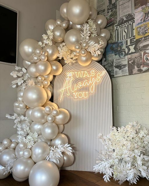 balloons and flowers on a table in front of a wall