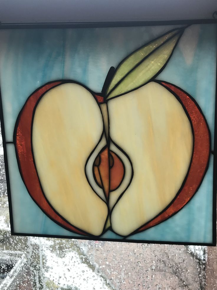 a stained glass window with an apple on it's side and a leaf sticking out of the center