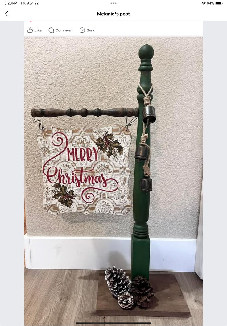 a green pole with pine cones on top and a merry christmas sign hanging from it