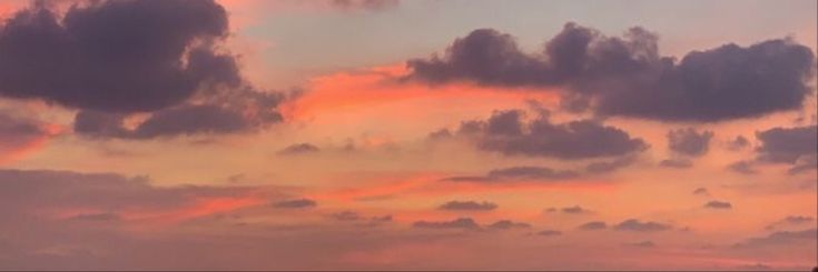 an airplane is flying in the sky with clouds above it at sunset or sunrise time