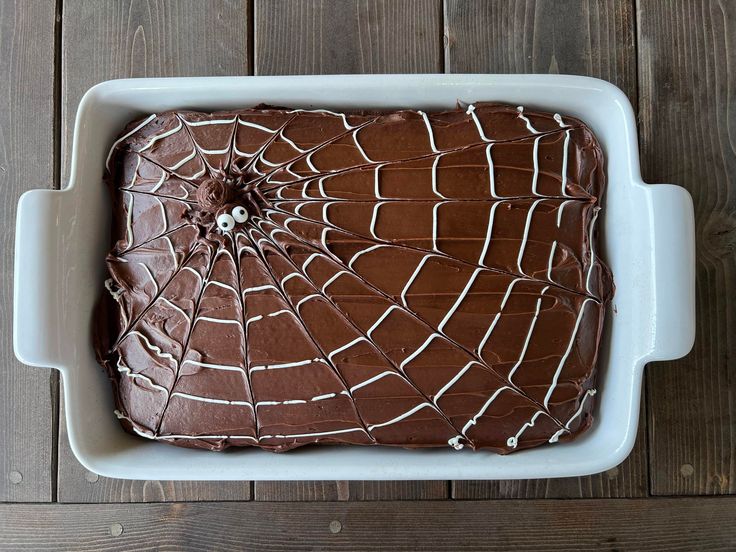 a spider web cake in a white dish on a wooden table