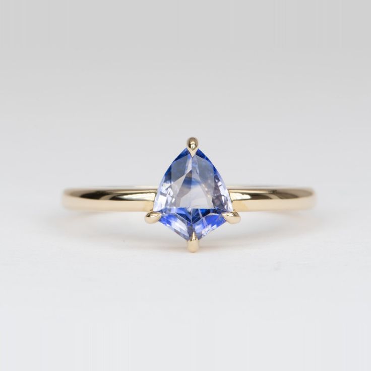 a yellow gold ring with a blue topazte in the center and two white diamonds at the bottom