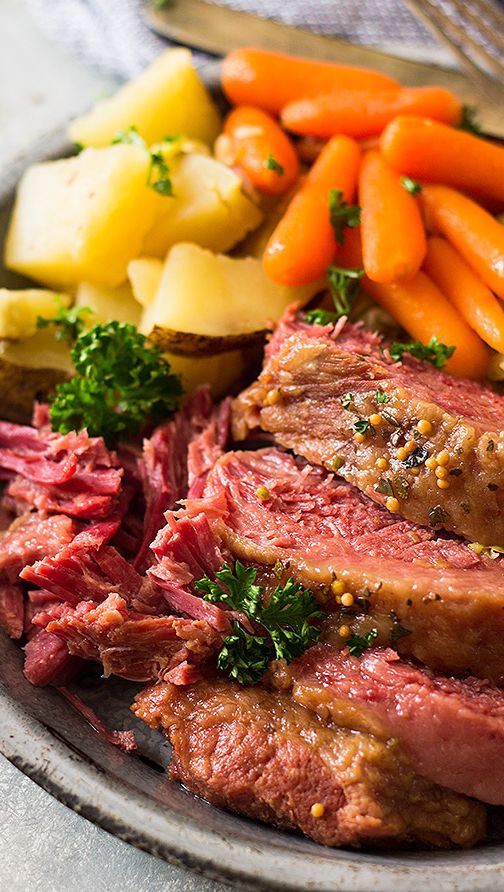 roast beef with carrots, potatoes and parsley on a plate next to other vegetables