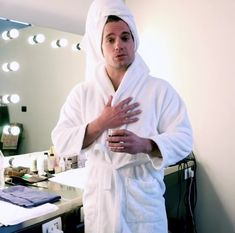 a man in a bathrobe standing next to a mirror