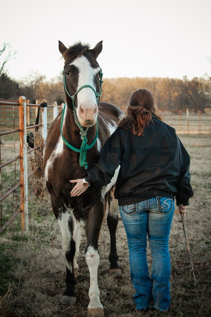 a woman is walking her horse in the field