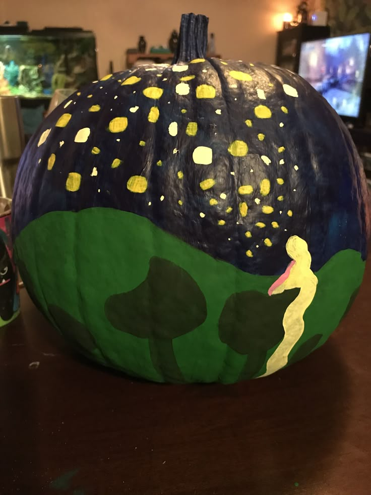 a painted pumpkin sitting on top of a wooden table