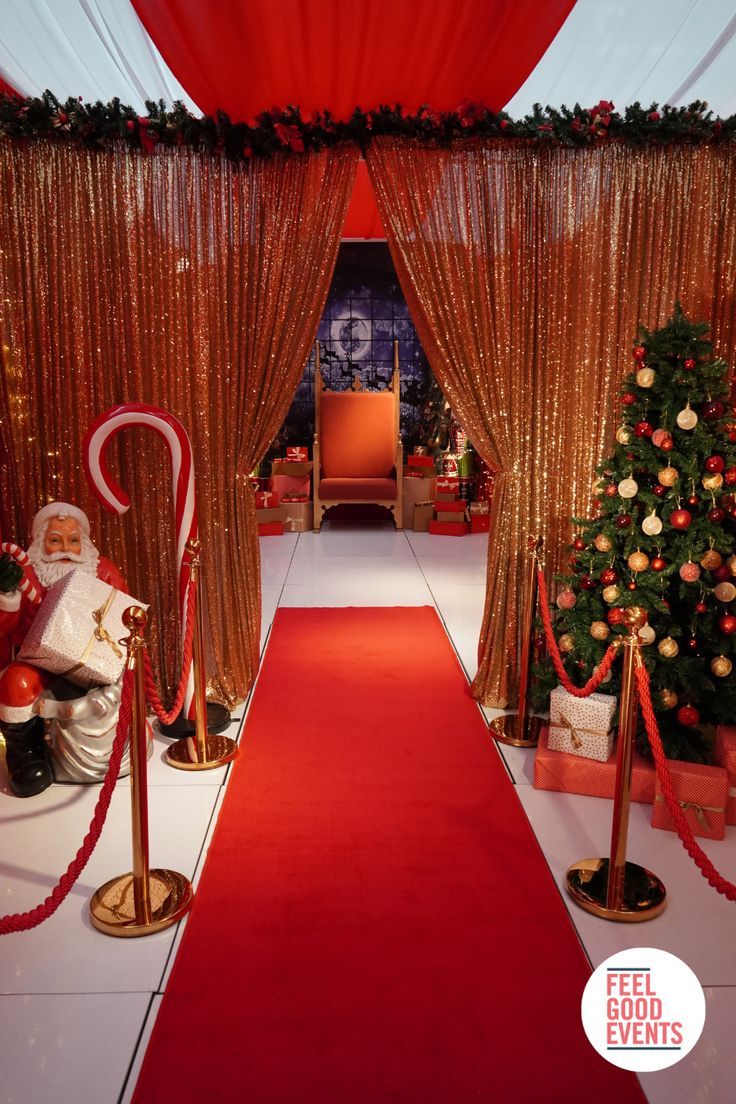 a red carpeted entrance way to a christmas themed event with decorations and trees on either side