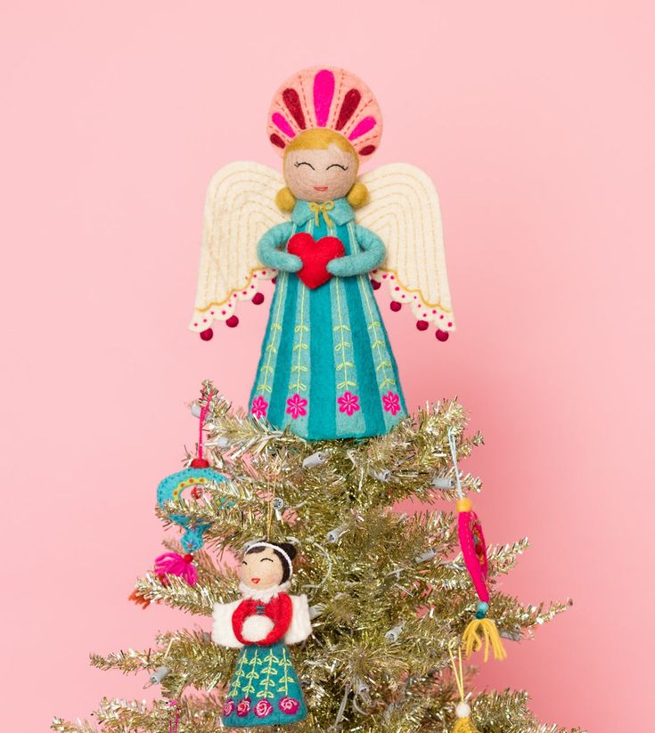 an angel figurine sitting on top of a christmas tree