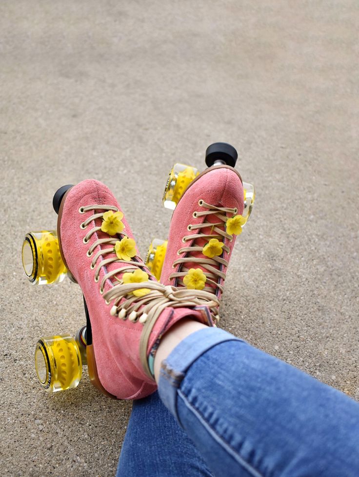 a person wearing pink boots and yellow laces on their feet with roller skates