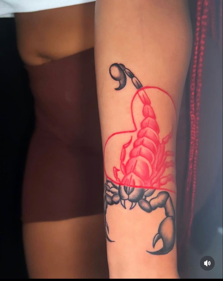 a woman's arm with a scorpion tattoo on it and a heart in the middle