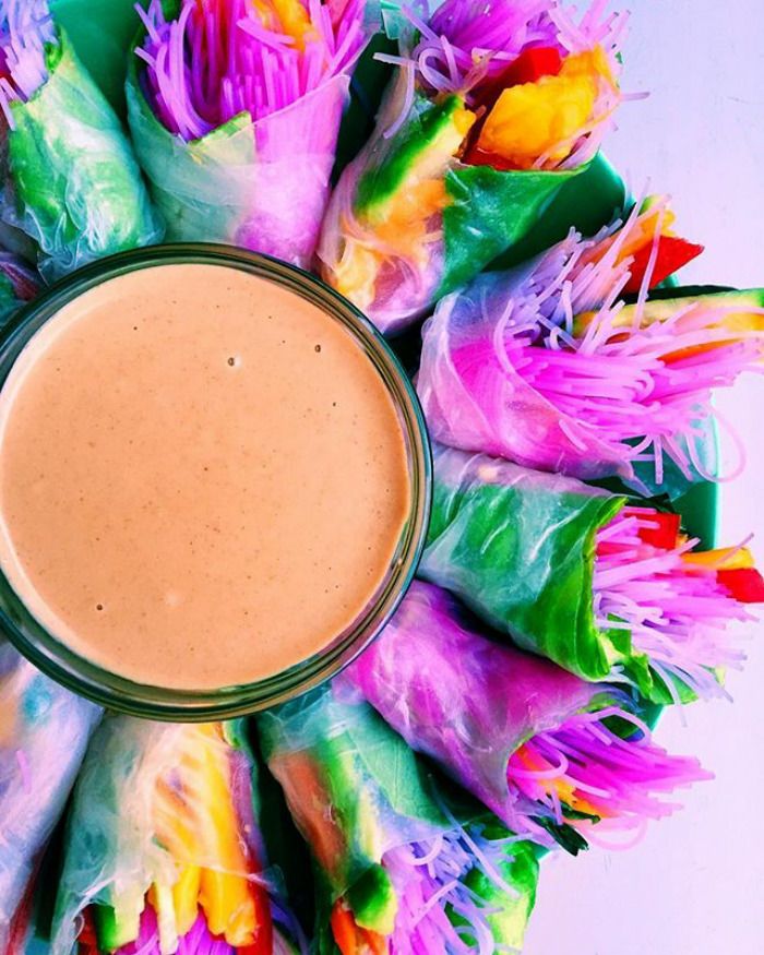 a glass filled with liquid sitting on top of colorful food wrappers and surrounded by multicolored flowers