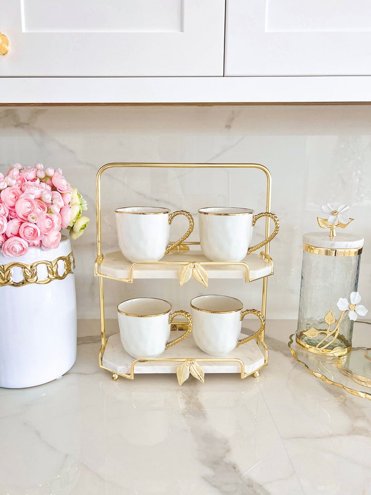 there are cups and vases on the counter in this kitchen with gold trimming