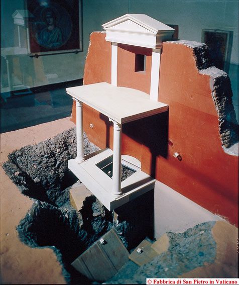 a white bird house sitting on top of a pile of rubble next to a red wall