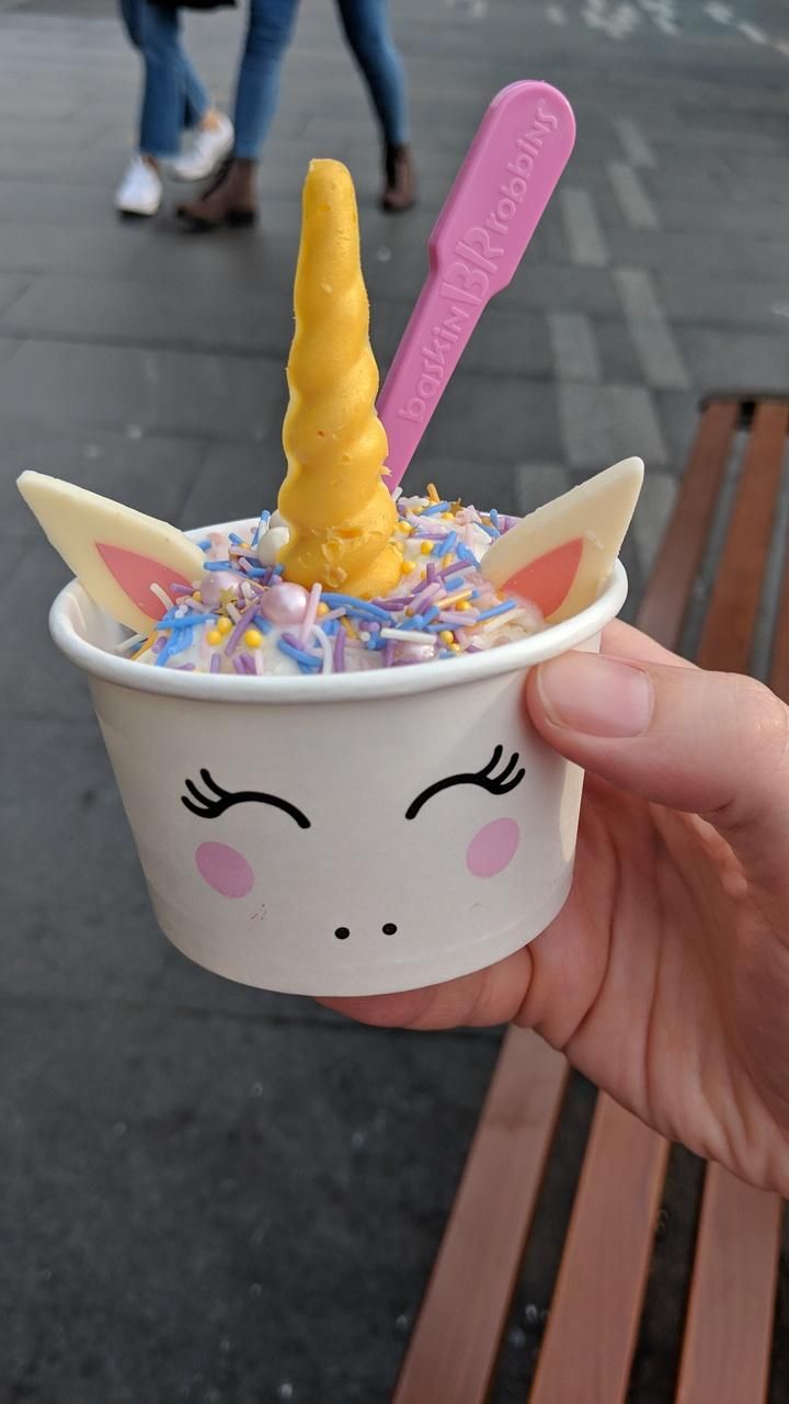 someone holding up a cup with unicorn ice cream in it