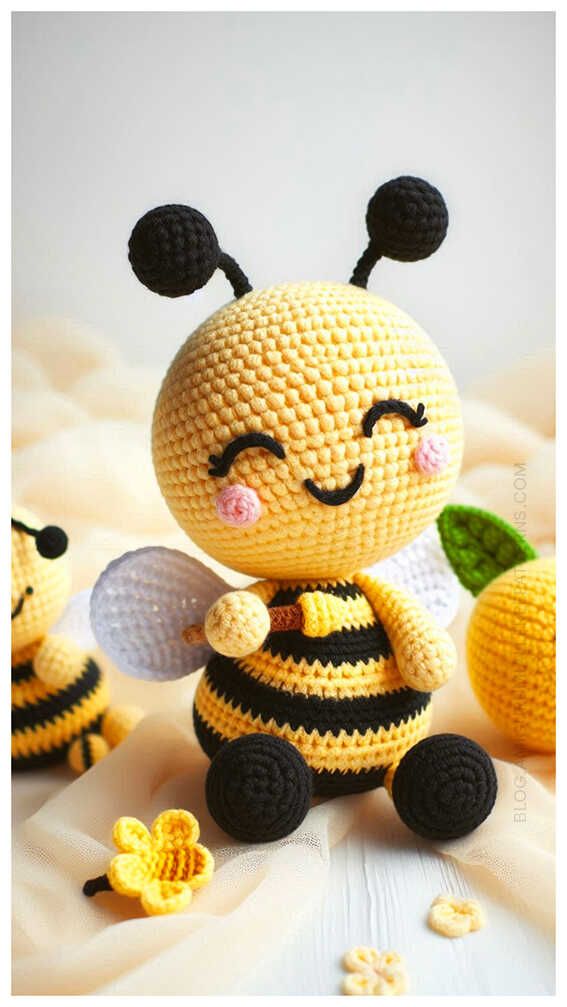 a crocheted bee sitting on top of a bed next to two small bees