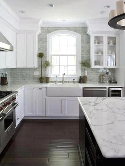 a kitchen with marble counter tops and white cabinets, along with stainless steel stove top ovens