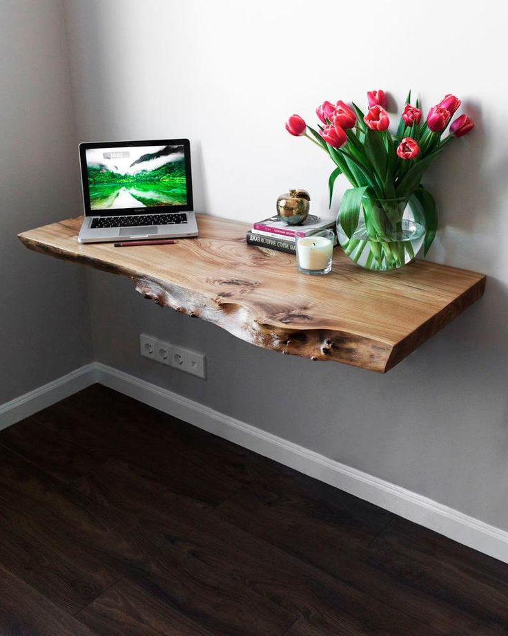 a laptop computer sitting on top of a wooden desk next to a vase with flowers