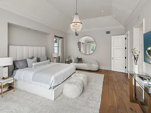 a bedroom with a large white bed in it's center and a mirror on the wall