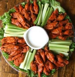 a platter filled with chicken wings and celery sticks next to a bowl of ranch dressing