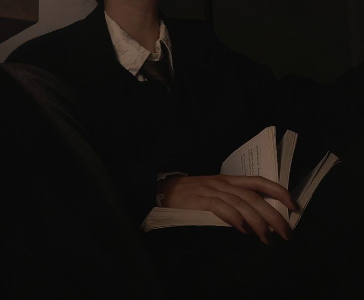 a person sitting down reading a book in the dark