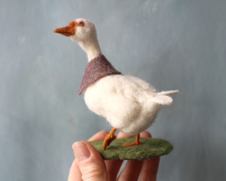 a small white bird sitting on top of a green piece of grass in someone's hand