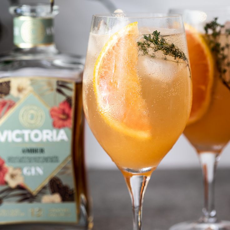 two wine glasses filled with oranges and herbs