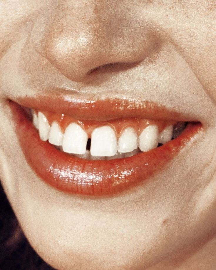 a close up of a woman's mouth with white teeth and orange lipstick on it