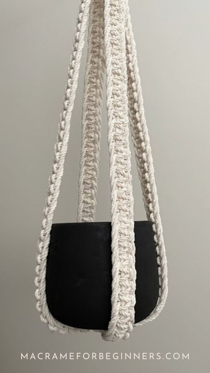 a black and white purse hanging from a rope on a gray wall with the words macrame for beginners written below it