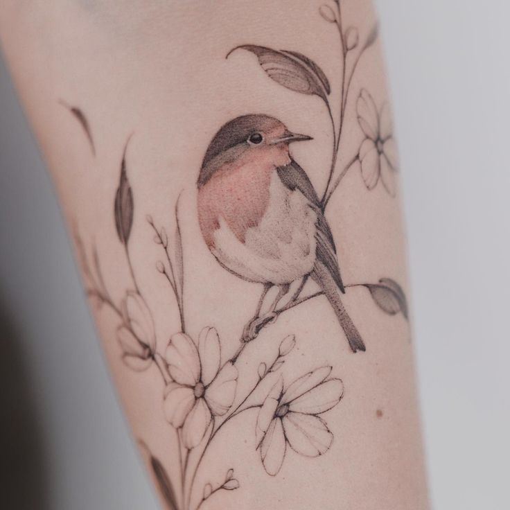 a small bird sitting on top of a branch with leaves and flowers around its neck