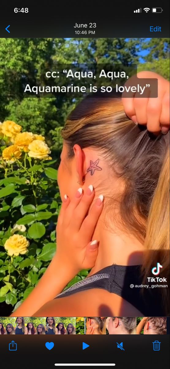 a woman with tattoos on her left ear and behind her ear is a yellow rose