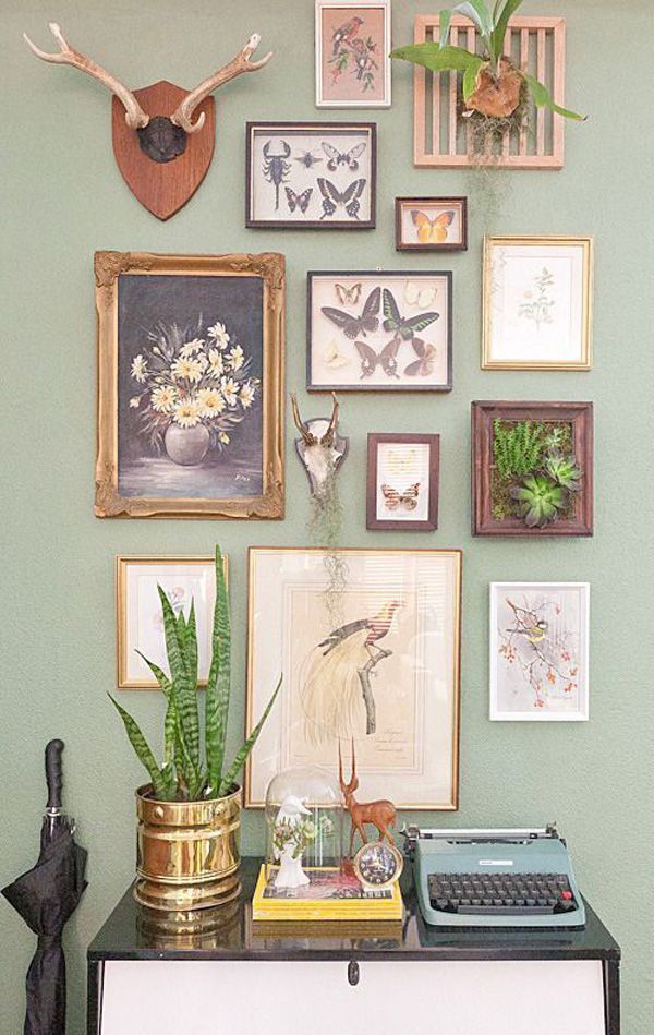 a green wall with pictures, plants and an old typewriter on it's desk