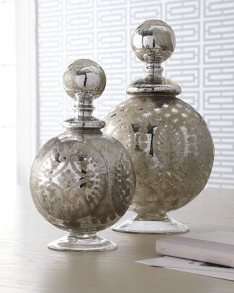 two silver vases sitting on top of a table next to a book and window