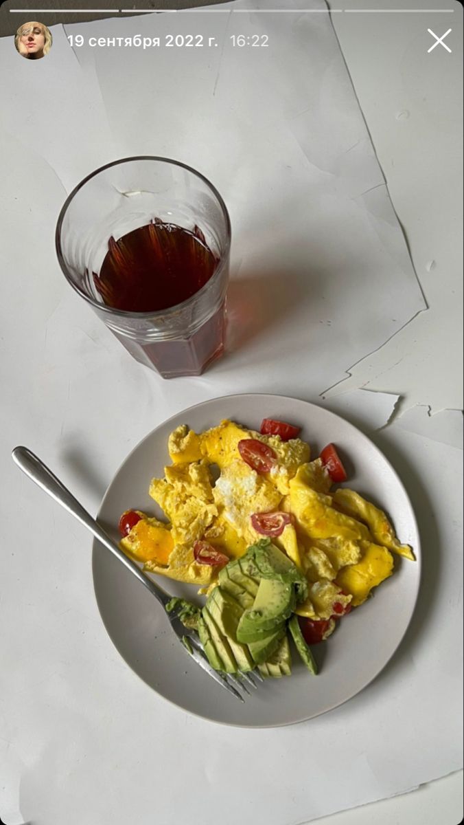 a white plate topped with eggs and vegetables next to a cup of tea on top of a table