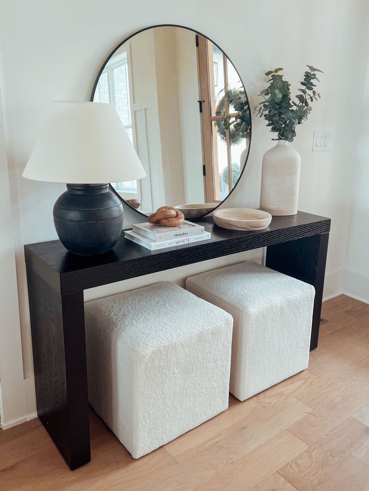 a black table with two stools and a round mirror