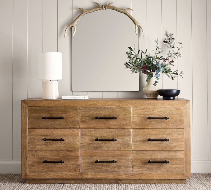 a wooden dresser with a mirror and vase on top