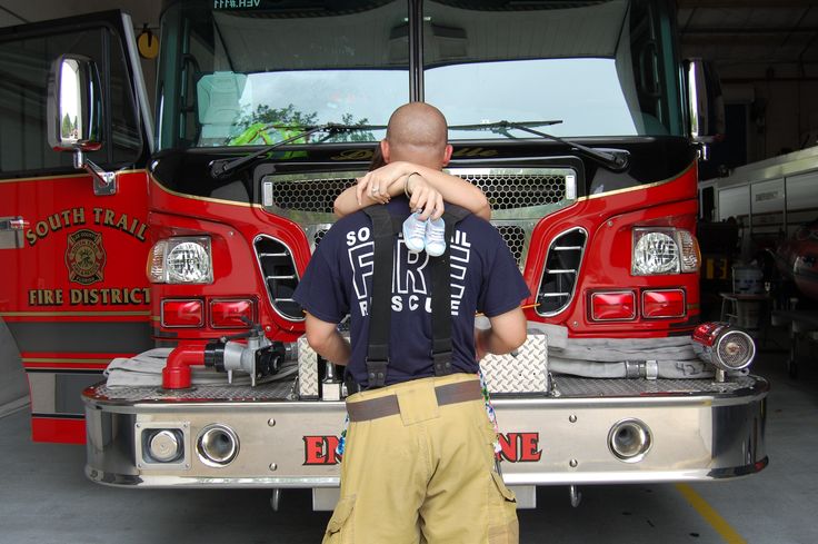 two fire fighters hugging each other in front of a fire truck with its hood up