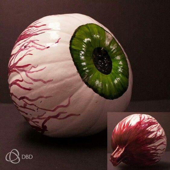 an onion with a green eye and red streaks on it's outer half is shown