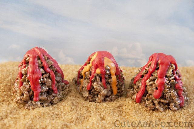 three donuts covered in red and yellow glazes on top of some sand