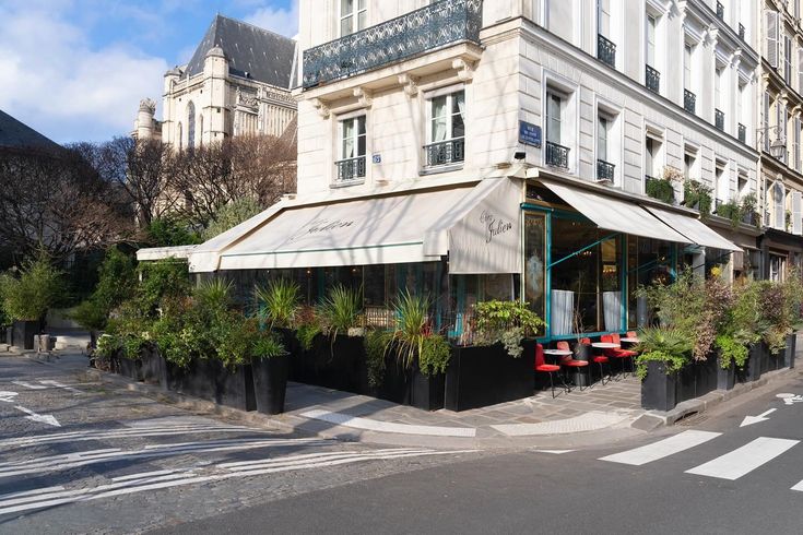 an empty street in front of a building with plants growing on the side of it