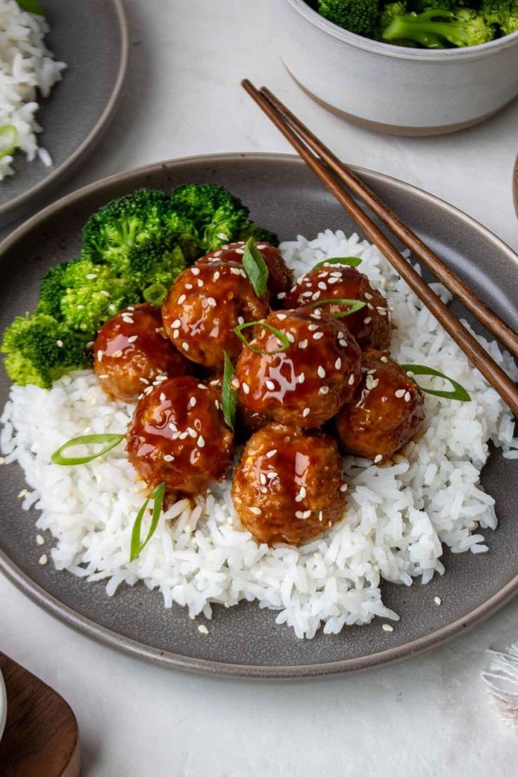 meatballs and broccoli are served on rice with chopsticks