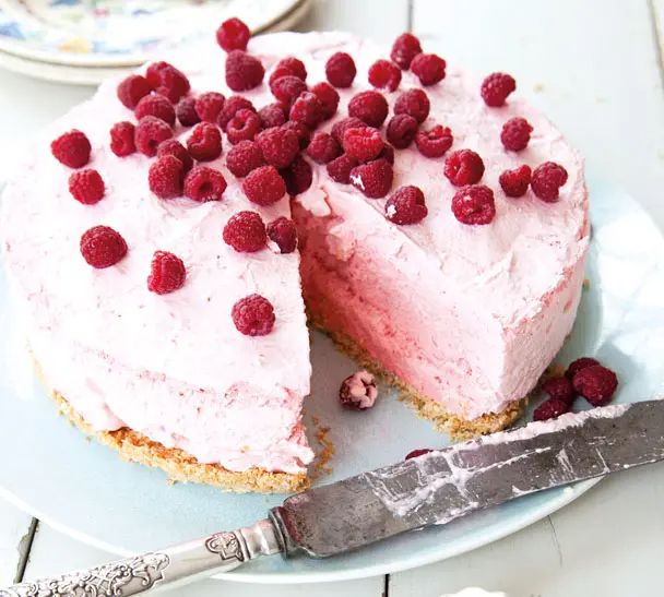 there is a cake with raspberries on it and a knife next to it