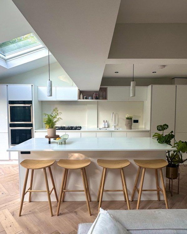 three stools are in front of the kitchen counter top and island with potted plants on it