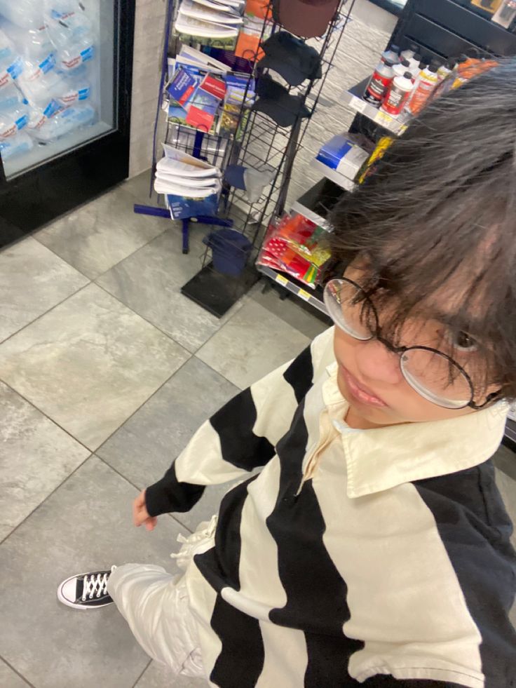 a woman wearing glasses and a black and white striped shirt is standing in front of a vending machine